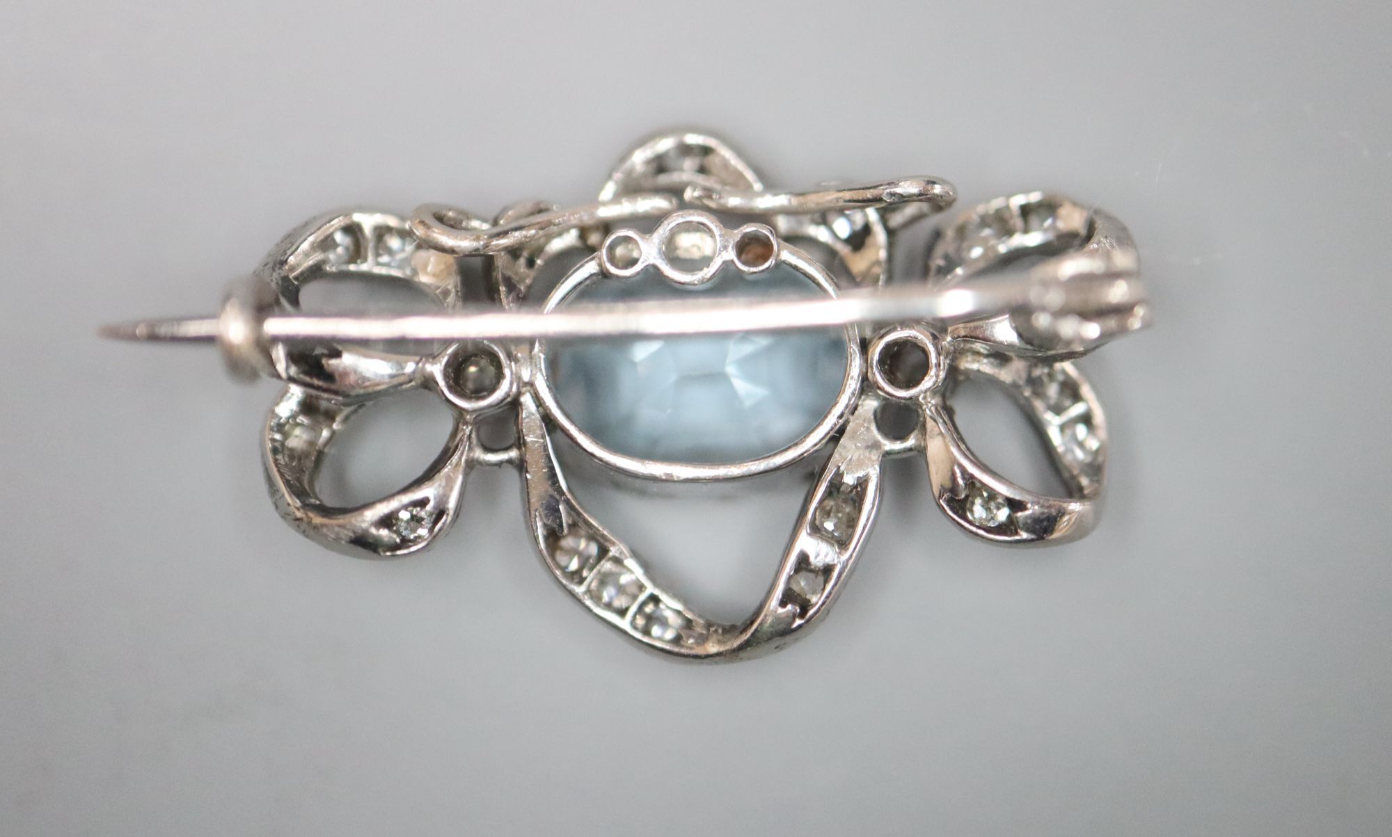 An Edwardian white metal, aquamarine and diamond set scroll brooch, 25mm, gross 3.8 grams.